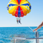 Happy couple Parasailing in Dominicana beach in summer. Couple under parachute hanging mid air. Having fun. Tropical Paradise. Positive human emotions, feelings, joy.